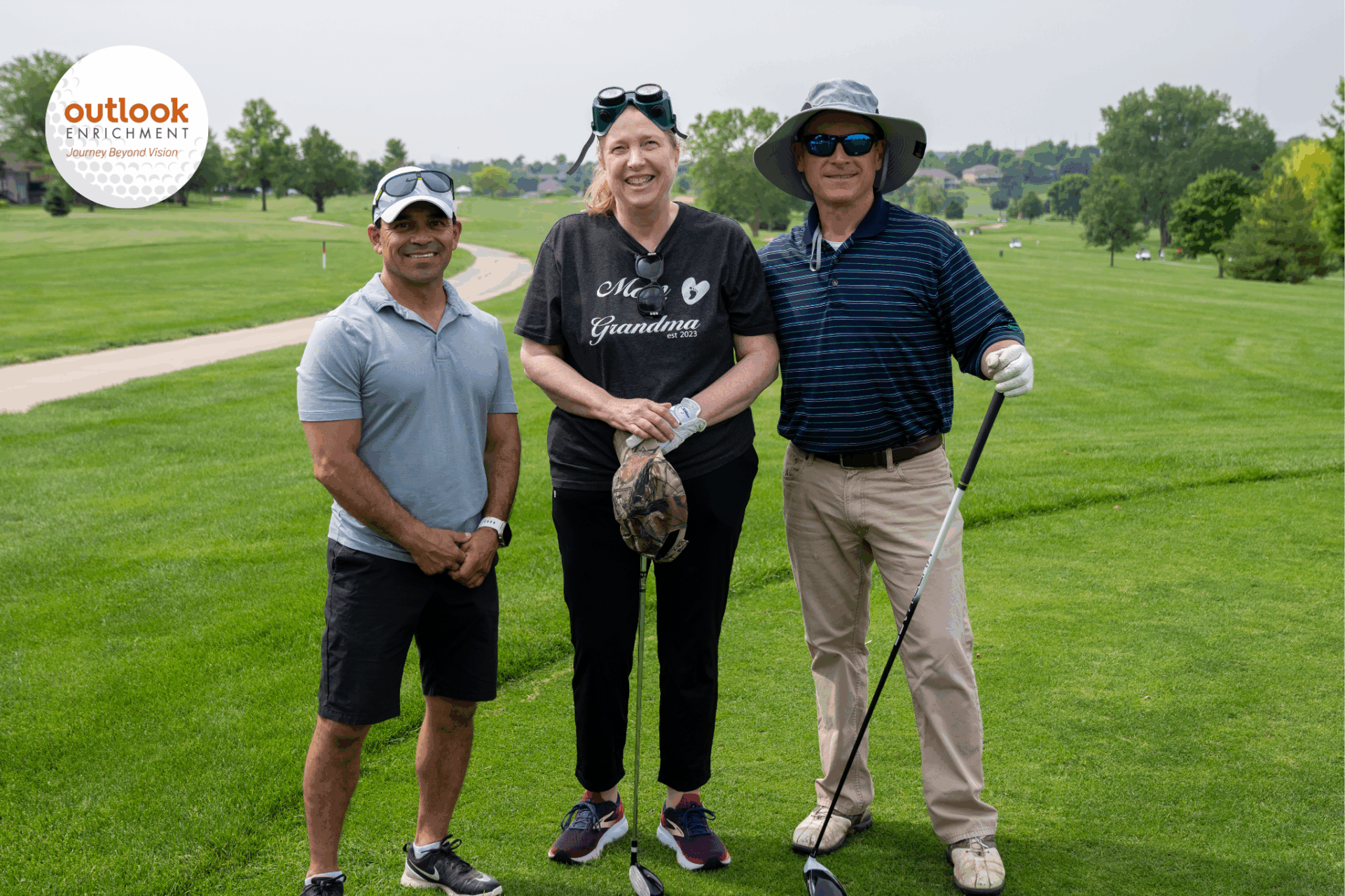 A Blind Golfers Clinic Team with two male volunteers and one female golfer in the middle, wearing vision immersion goggles.