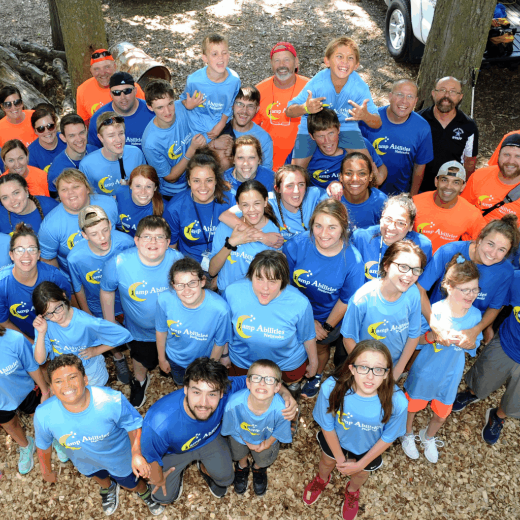 A group shot of campers and volunteers standing in rows, smiling and looking up at the camera.