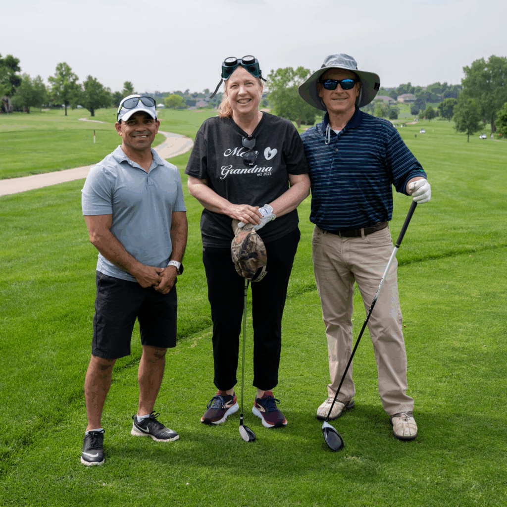 A Blind Golfers Clinic Team with two male volunteers and one female golfer in the middle, wearing vision immersion goggles.